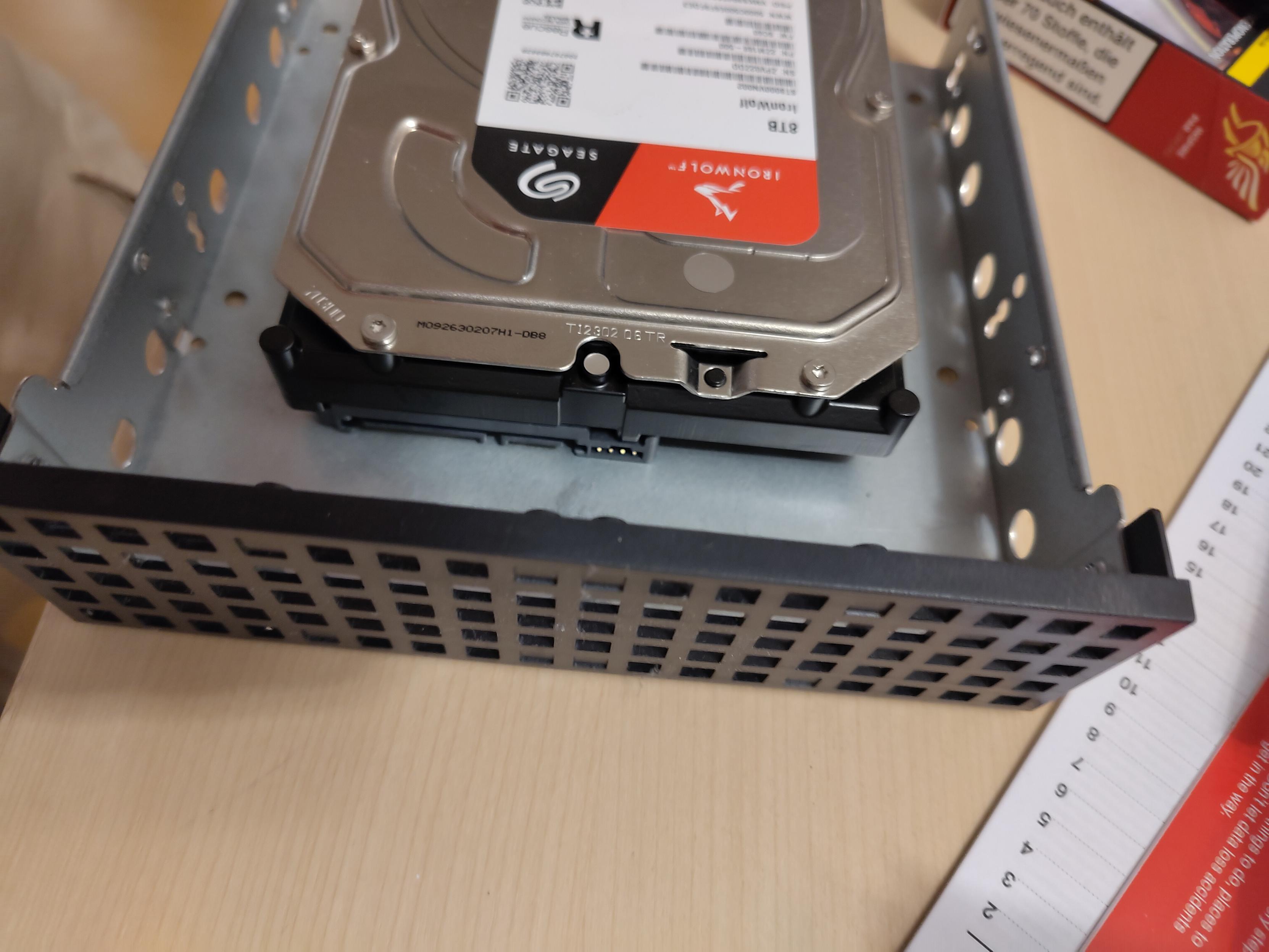 A picture of an HDD installed into a drive caddy. Notably, the HDD's connectors point towards the ventilation grill at the front of the caddy, instead of the open back.