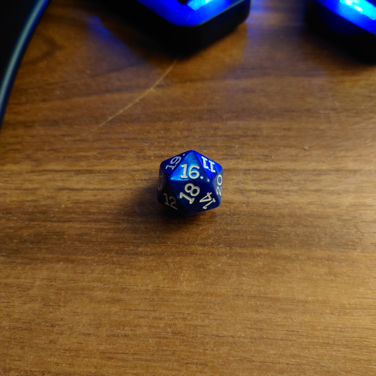 A picture of a 20 sided dice with the number 16 on the upper face.