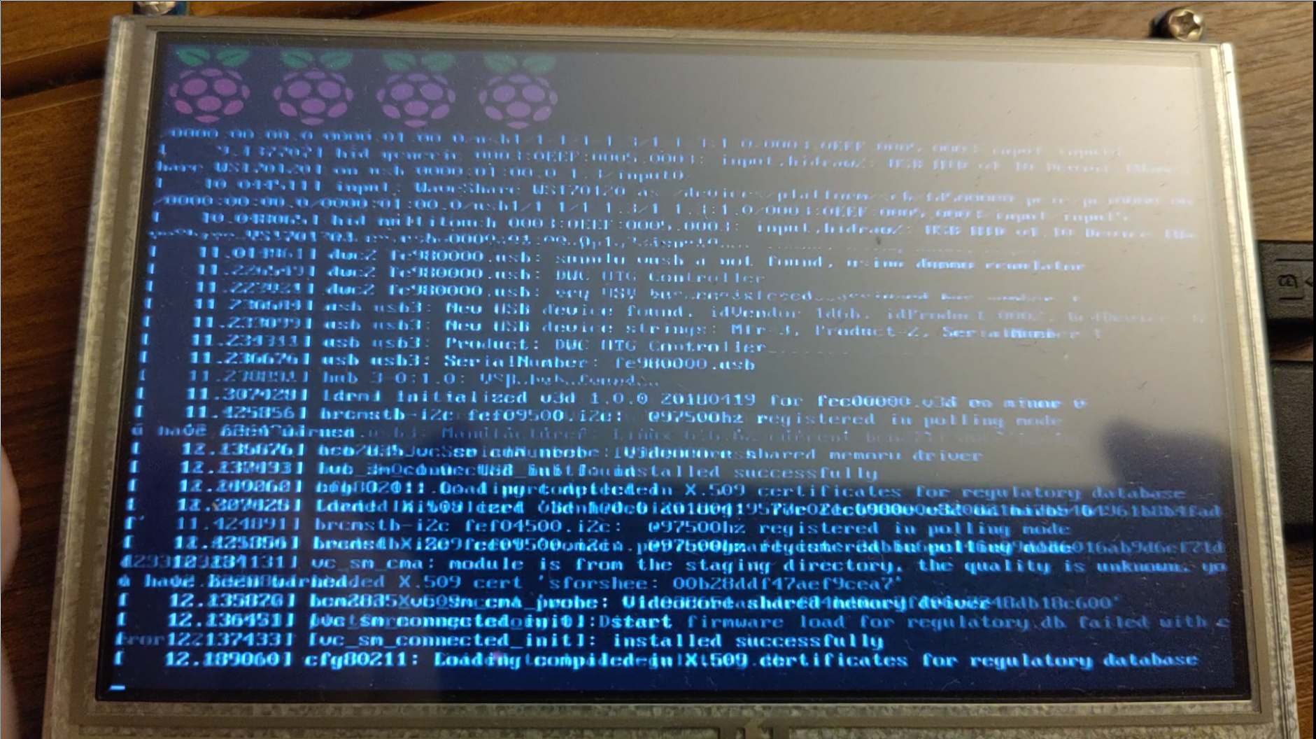 A picture of a small screen showing Linux kernel startup logs. The output is all jumbled up, with previous lines still partially visible, faded under the current lines.