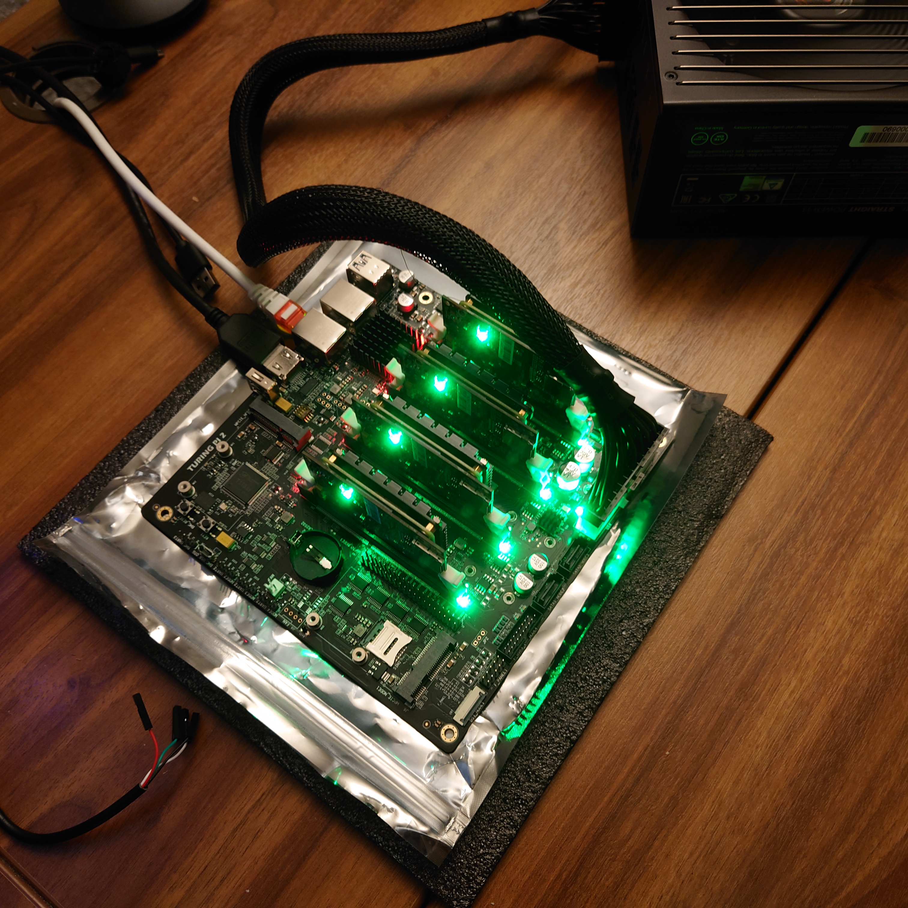 A picture of a Turing Pi 2 board with four CM4 modules attached, with green LEDs blinking away on all four.